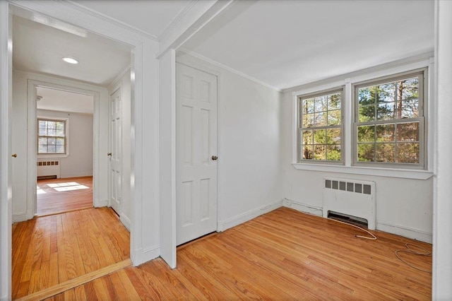 interior space featuring ornamental molding, light wood finished floors, radiator heating unit, and baseboards