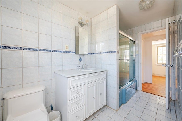 bathroom featuring toilet, tile patterned floors, tile walls, and vanity