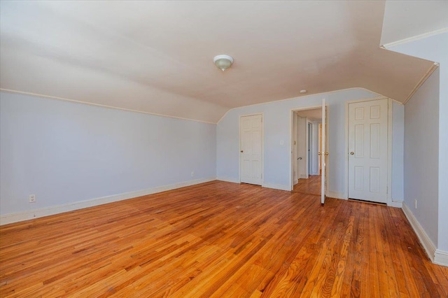 bonus room featuring baseboards, vaulted ceiling, and light wood finished floors