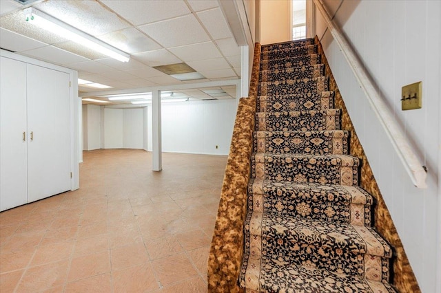 staircase with a paneled ceiling