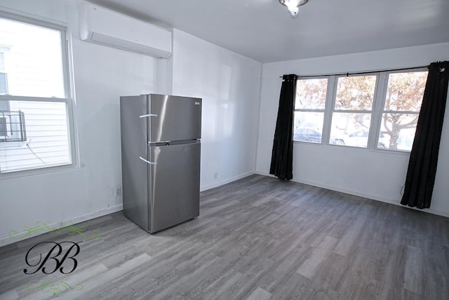 kitchen with stainless steel refrigerator, a healthy amount of sunlight, and wood-type flooring