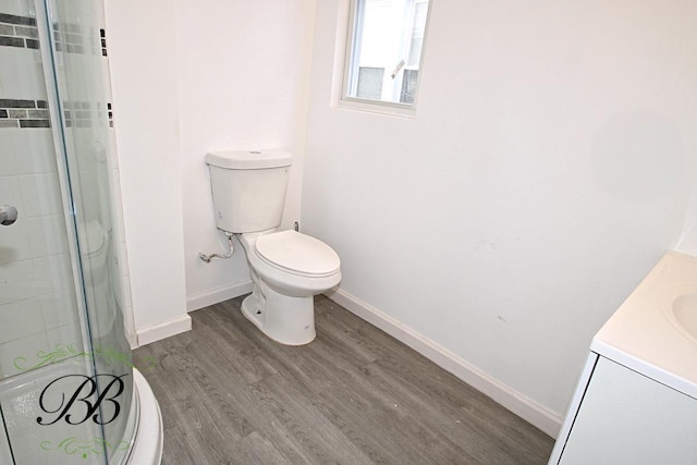 bathroom featuring vanity, wood-type flooring, a shower with shower door, and toilet