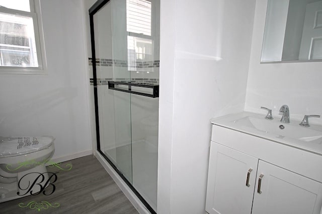 bathroom featuring toilet, vanity, a shower with shower door, and wood-type flooring