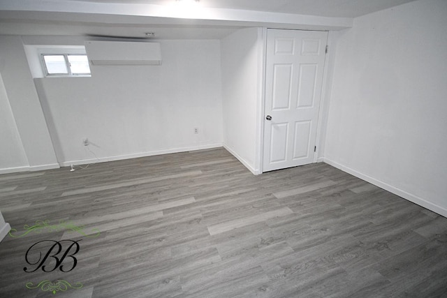 basement featuring hardwood / wood-style floors and a wall mounted air conditioner