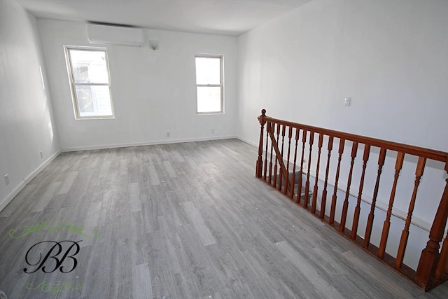 unfurnished room with light wood-type flooring and an AC wall unit