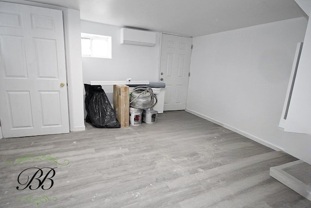 basement featuring a wall unit AC and light hardwood / wood-style floors