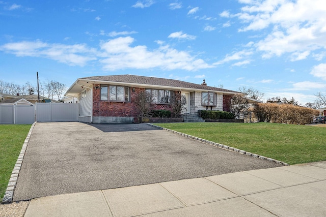 ranch-style house with aphalt driveway, brick siding, a gate, fence, and a front lawn