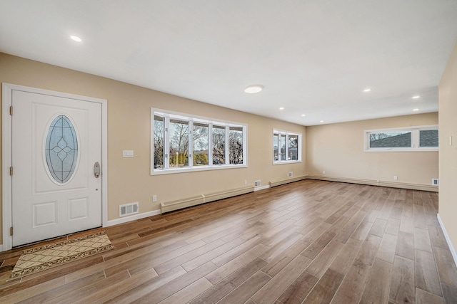 entrance foyer with light wood-type flooring, visible vents, a baseboard heating unit, and baseboards