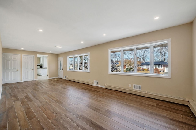 unfurnished living room featuring light wood-style floors, a baseboard radiator, visible vents, and recessed lighting