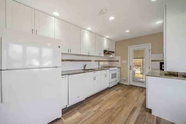 kitchen with dark stone counters, white appliances, visible vents, and white cabinets