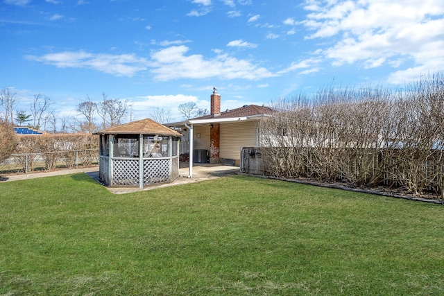 rear view of house with a yard, a chimney, a gazebo, and fence