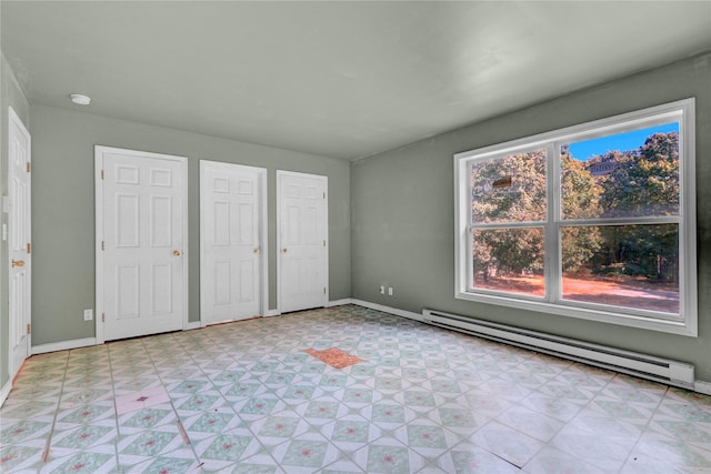 unfurnished bedroom with a baseboard heating unit and two closets