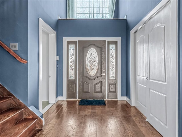 entrance foyer featuring hardwood / wood-style flooring, visible vents, a high ceiling, and stairs