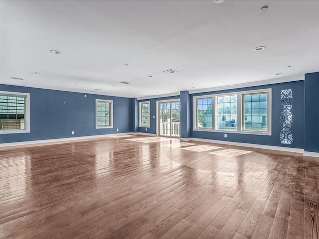 unfurnished living room featuring visible vents, baseboards, and wood finished floors