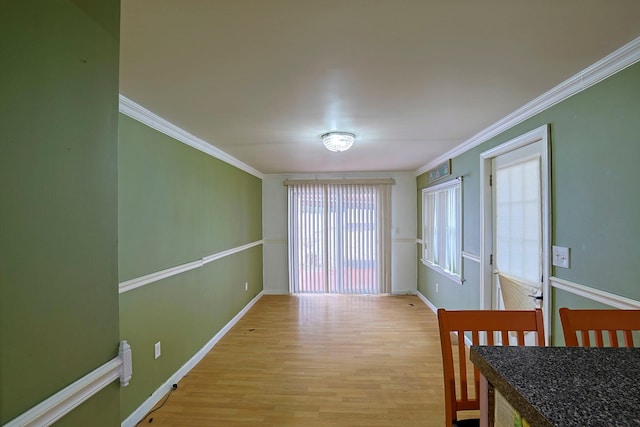 interior space with ornamental molding, light wood-type flooring, and baseboards