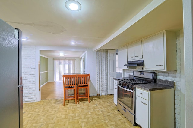 kitchen with stainless steel appliances, dark countertops, white cabinets, and under cabinet range hood