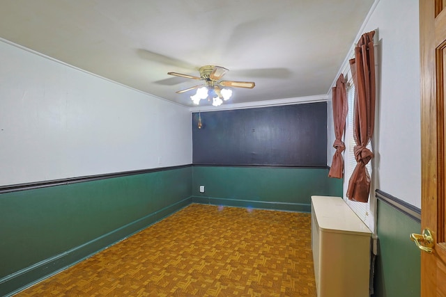 spare room with wainscoting and a ceiling fan