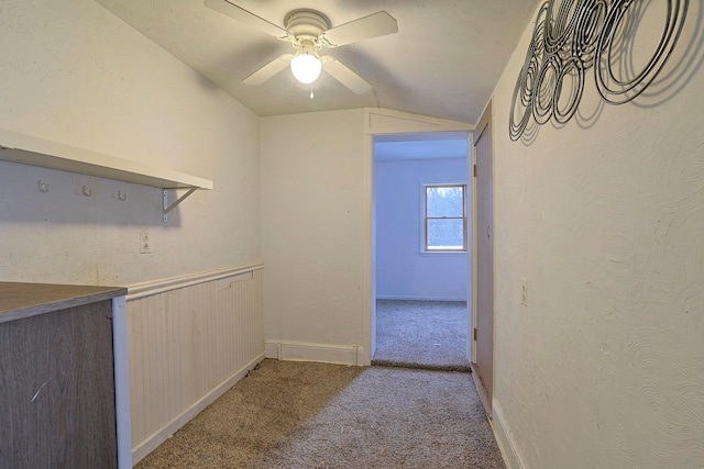 hallway featuring lofted ceiling, a textured wall, and carpet