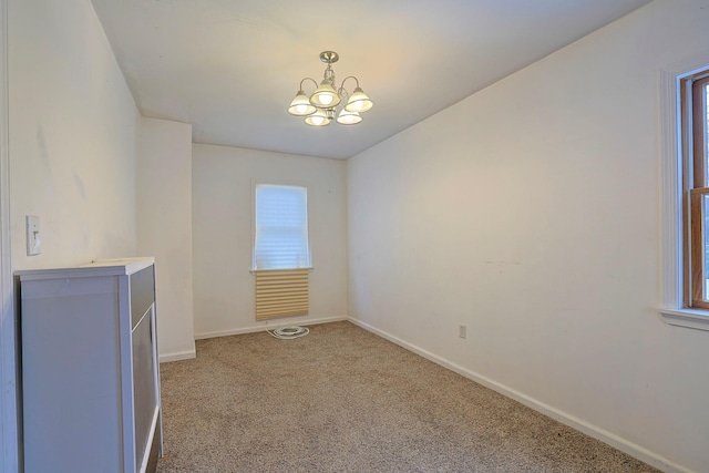 carpeted spare room with baseboards and a chandelier