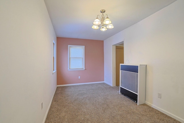 spare room featuring light carpet, a notable chandelier, and baseboards