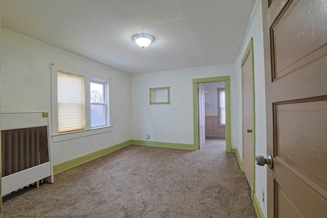 spare room with carpet, crown molding, and baseboards