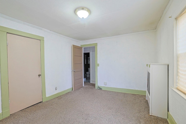 unfurnished room with ornamental molding, carpet flooring, and baseboards