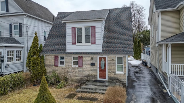 view of front of house featuring stone siding and roof with shingles