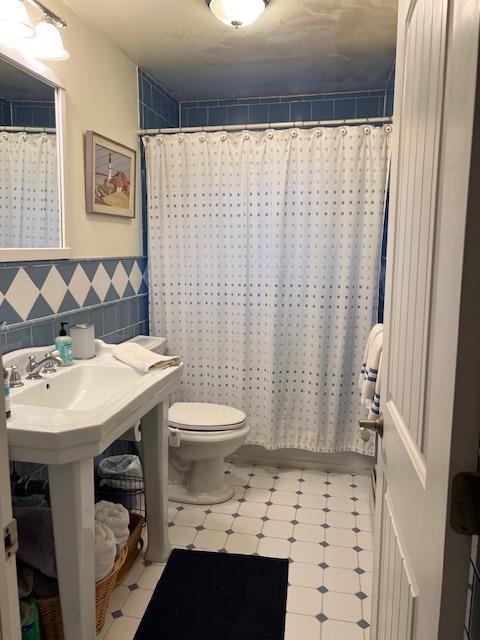 bathroom featuring tile walls, toilet, and walk in shower