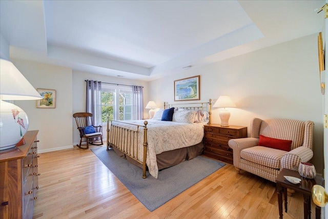 bedroom featuring a raised ceiling and light hardwood / wood-style floors