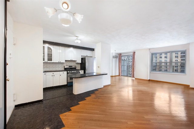 kitchen featuring hardwood / wood-style floors, white cabinetry, pendant lighting, stainless steel appliances, and tasteful backsplash