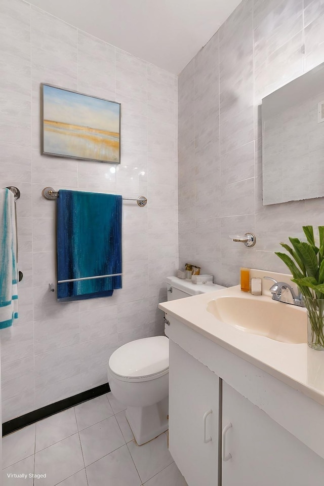 bathroom featuring toilet, tile patterned floors, tile walls, and vanity