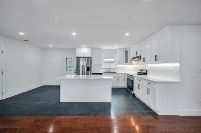 kitchen featuring white cabinetry, a kitchen island, sink, backsplash, and appliances with stainless steel finishes