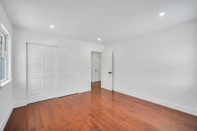 unfurnished bedroom featuring multiple windows, a closet, and hardwood / wood-style floors