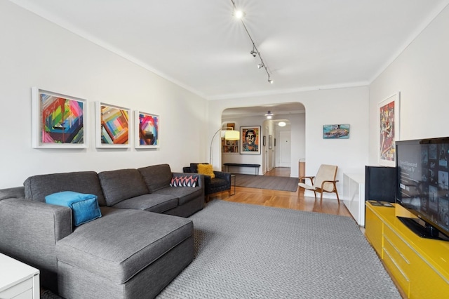 living area featuring track lighting, arched walkways, and wood finished floors