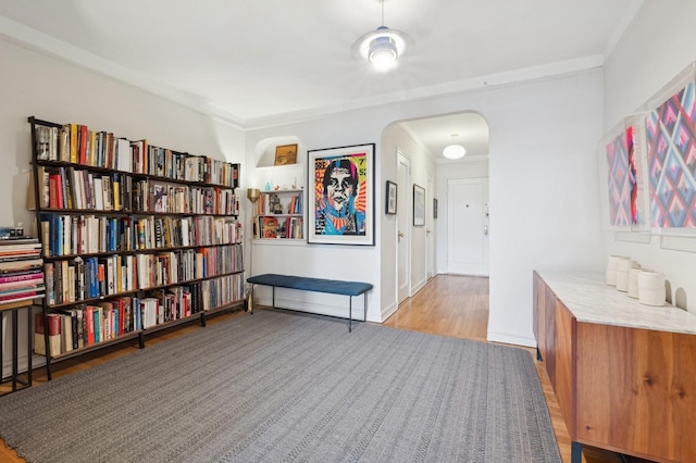 living area featuring light wood-style floors, arched walkways, and baseboards