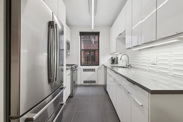 kitchen with white cabinets, radiator, modern cabinets, appliances with stainless steel finishes, and a sink