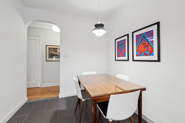 dining room featuring dark wood-style floors, arched walkways, and baseboards