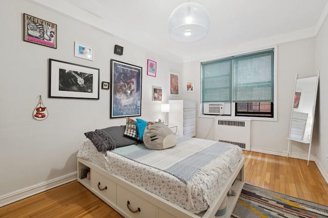 bedroom featuring radiator, light wood-type flooring, and baseboards