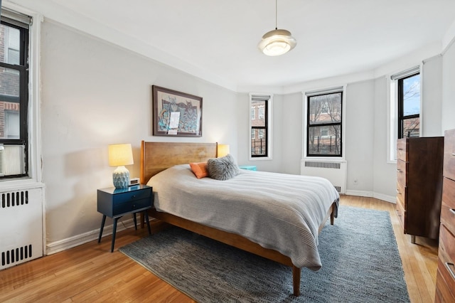 bedroom featuring radiator, light wood finished floors, and multiple windows