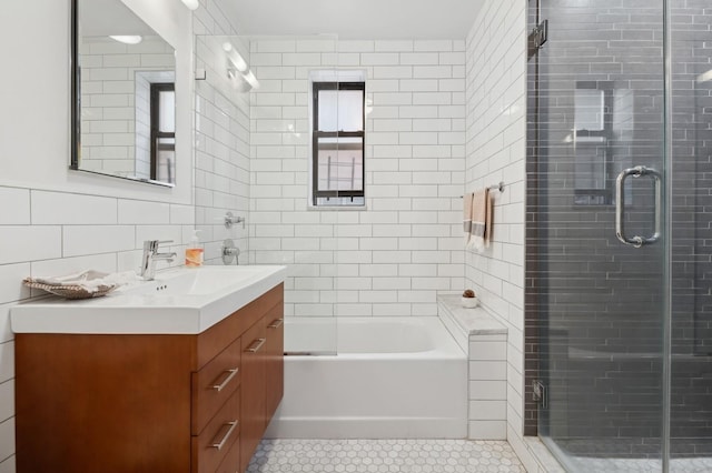 bathroom with tile patterned flooring, a bathing tub, vanity, tile walls, and a shower with door