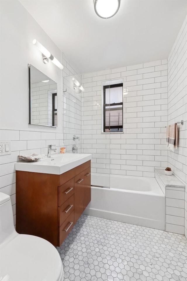 full bathroom with tile patterned flooring, toilet, vanity, tile walls, and washtub / shower combination