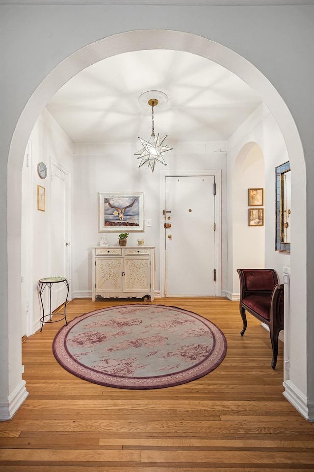 entrance foyer with baseboards, a chandelier, and wood finished floors