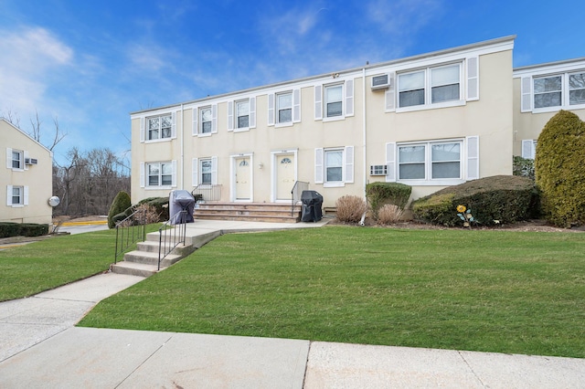 view of property with a wall mounted air conditioner, a front lawn, and stucco siding