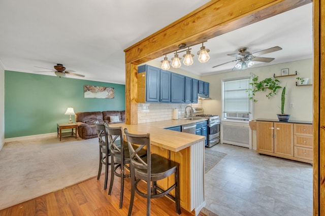 kitchen featuring a breakfast bar area, blue cabinets, a peninsula, stainless steel appliances, and open floor plan