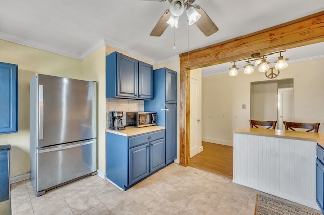 kitchen featuring light countertops, appliances with stainless steel finishes, hanging light fixtures, and blue cabinetry