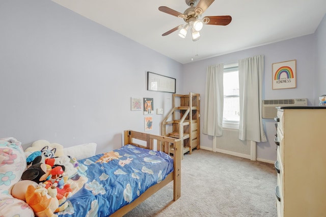 bedroom featuring light carpet, a wall unit AC, baseboards, and a ceiling fan