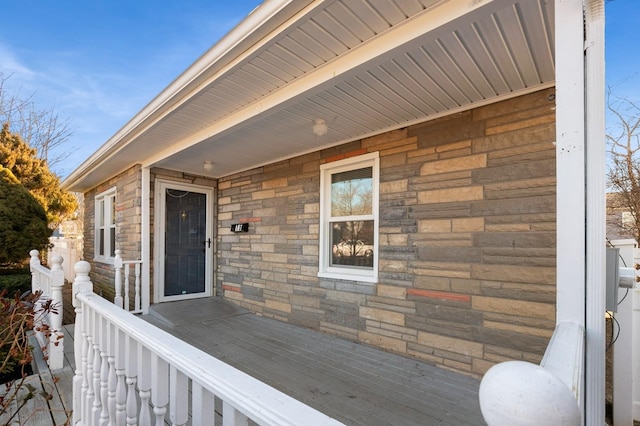 property entrance with stone siding and a wooden deck