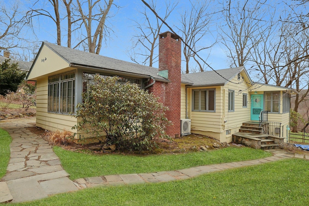 view of front of home featuring a chimney, a sunroom, and ac unit
