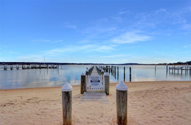 view of dock with a beach view and a water view