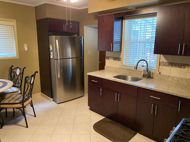 kitchen with stainless steel refrigerator, light stone countertops, sink, ornamental molding, and tasteful backsplash